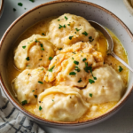 A bowl of slow cooker chicken and dumplings with tender chicken and fluffy dumplings in a creamy broth.