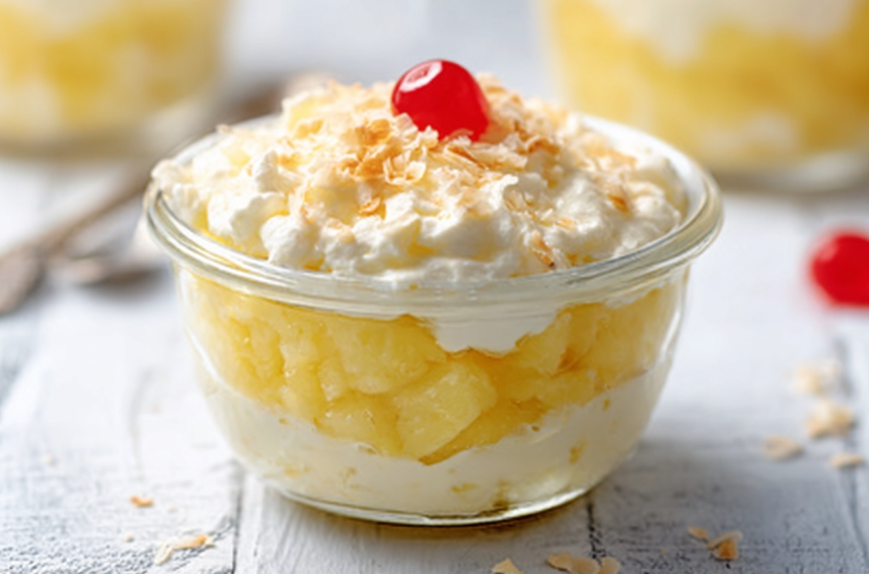 A vibrant bowl of easy pineapple dessert, garnished with fresh pineapple chunks and shredded coconut, ready to serve.